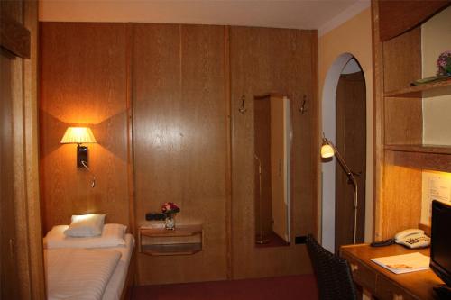 a hotel room with a bed and a desk with a lamp at Hotel und Restaurant Post Prienbach in Stubenberg