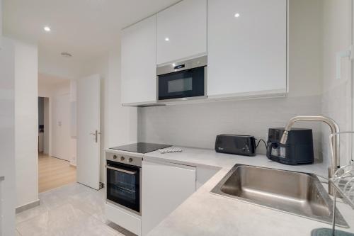 une cuisine blanche avec un évier et un micro-ondes dans l'établissement Newly renovated charming downtown apartment, à Antibes