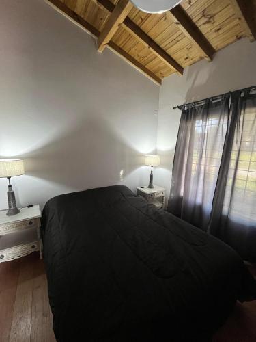 a bedroom with a black bed and two tables with lamps at Casita Amarilla in Miramar