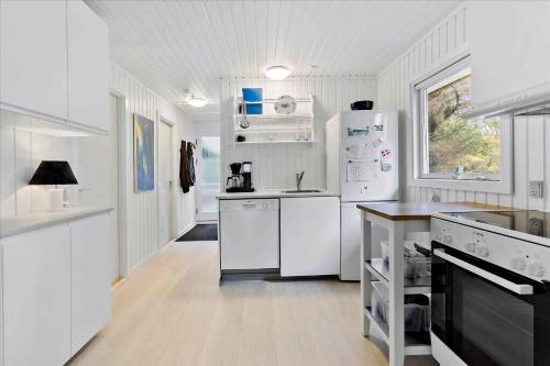 a white kitchen with white appliances and white cabinets at Unobstructed Summer House In Lovely Langeland in Tranekær