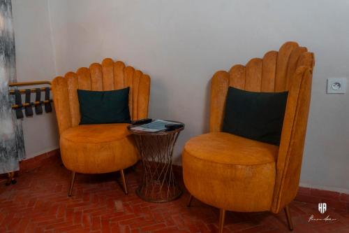 two wooden chairs and a side table in a room at PALACIO AL ANDALUS in Chefchaouene