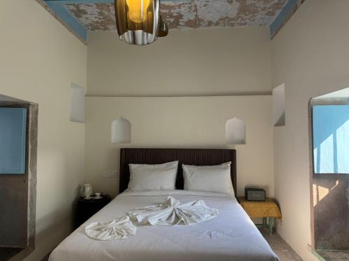 a bedroom with a bed with white sheets and a ceiling at Rana Mahal - a Boutique Place in Varanasi