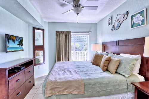 a bedroom with a bed with a ceiling fan and a window at Sunset Vistas 206S in St Pete Beach