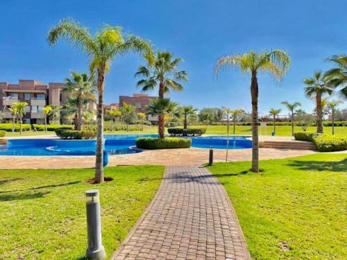 a brick path in a park with palm trees at Appartement Prestigia Agate résidence avec piscine in Marrakech