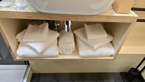 a shelf with white towels and a sink at RE Plai in Zărneşti