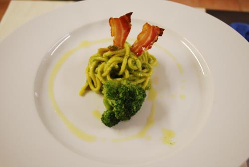 a white plate with pasta and broccoli on it at Hotel Borgo degli Olivi in Riotorto
