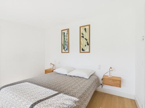 une chambre avec un lit et deux tableaux au mur dans l'établissement -OZARIO- Magnifique maison au Cabellou, à Concarneau
