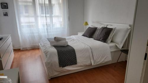 a white bed in a white room with a window at Swiss Flats in Lausanne