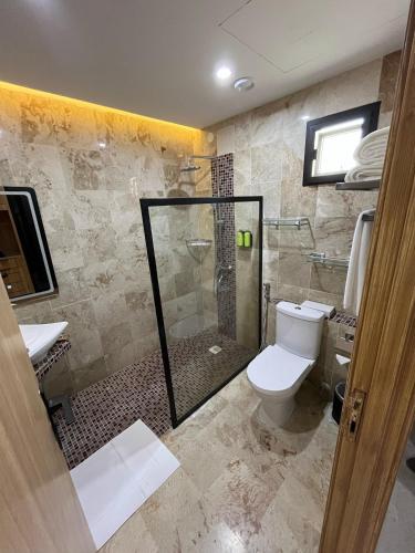 a bathroom with a toilet and a glass shower at Al Sawadi Beach Resort & Spa in Barka