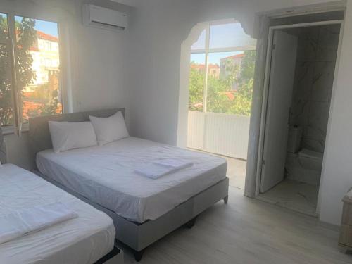 a white bedroom with two beds and a window at ULAŞ TWENTY Rooms in Edirne