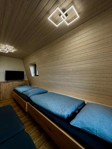 two beds in a room with a wooden wall at Chata ARMA in Vrbov
