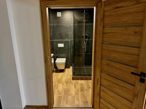 a bathroom with a shower and a toilet and a door at Chata ARMA in Vrbov
