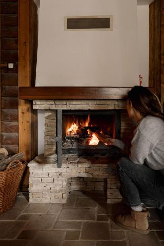 a woman squatting in front of a brick fireplace at Wild&Free Private Lake in Nagycsepely
