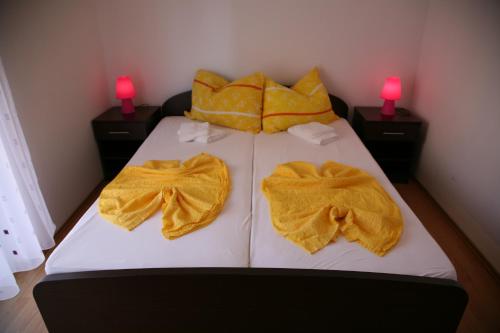 a bed with two yellow robes on it with two lamps at Vila in Lavanda in Fažana