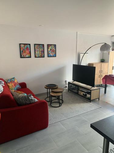 Il comprend un salon doté d'un canapé rouge et d'une télévision à écran plat. dans l'établissement Superb apartment 2 min from Richelieu Beach, Cap d'Agde, au Cap d'Agde