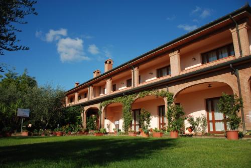 a large brick building with plants in a yard at Hotel Borgo degli Olivi in Riotorto