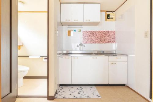 a small kitchen with white cabinets and a sink at Minowa Sta Direct to Ueno in Tokyo