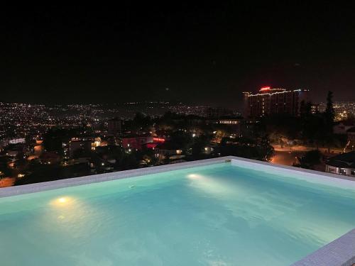 a swimming pool with a view of a city at night at Affordable Luxury Rooms with Pool, Gym and Office Space in Kigali