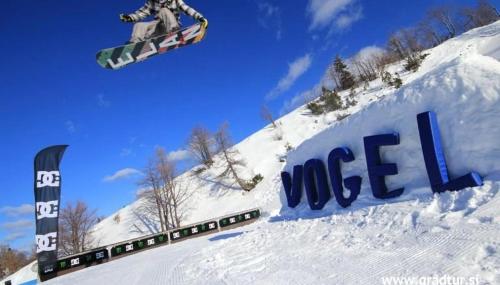 a person on a snowboard in the air over a sign at Bohinj River House in Bohinj