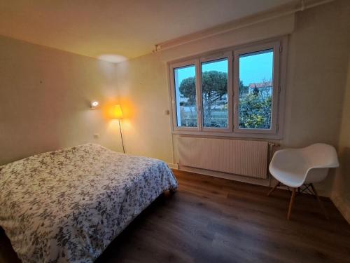 une chambre avec un lit, une chaise et une fenêtre dans l'établissement Les Portes de l'Océan, à Vaux-sur-Mer