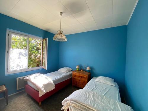 - une chambre bleue avec 2 lits et une fenêtre dans l'établissement Charmante maison landaise 6 pers. avec jardin, terrasse, proche plage - Capbreton - FR-1-413-221, à Capbreton