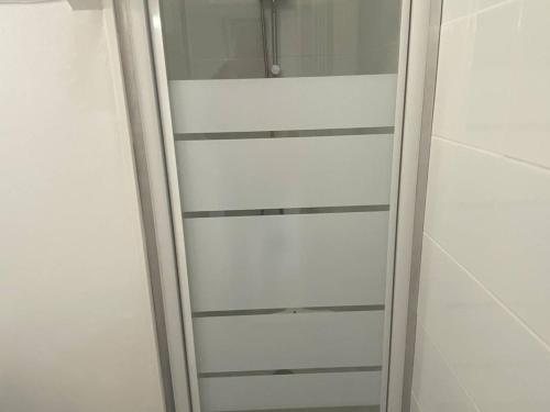 La salle de bains blanche est pourvue d'une porte de douche en verre. dans l'établissement T1 Bis Charmant à Bidart, 2 Pers, 900m Plage, Terrasse et Spa, Quartier Calme - FR-1-495-137, à Bidart