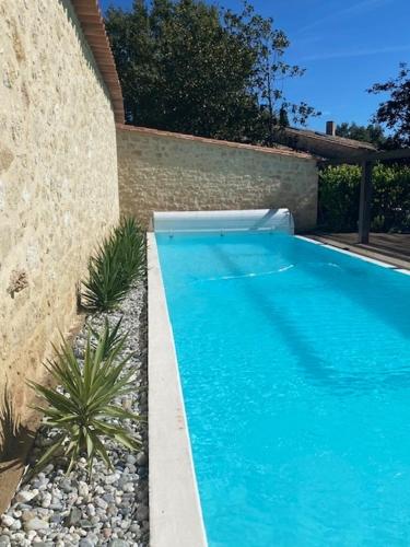 une grande piscine bleue à côté d'un mur dans l'établissement Maison de campagne Proche de St Emilion, à Montcaret