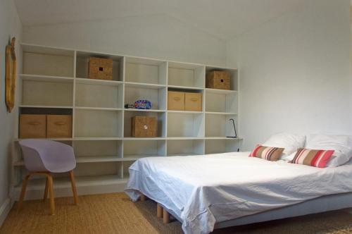a bedroom with a bed and shelves and a chair at Maison de campagne Proche de St Emilion in Montcaret