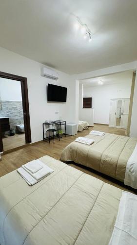 two beds in a room with a flat screen tv at Cala Portavecchia in Monopoli