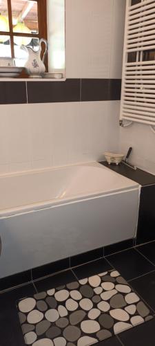 bagno con vasca e pavimento piastrellato bianco e nero. di Chambre d'Hote Les Touilles a Piégut-Pluviers