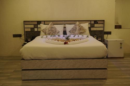 a large bed with white sheets and flowers on it at Sapphero Jungle Vista Resort - Sasan Gir in Sasan Gir