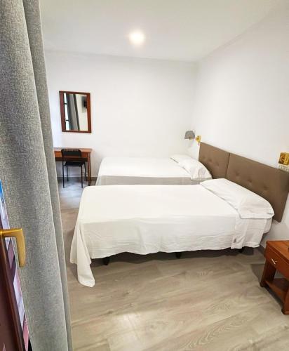Dos camas en una habitación de hotel con sábanas blancas. en Habitaciones triple familiar HOTEL LAUAXETA, en Mungia