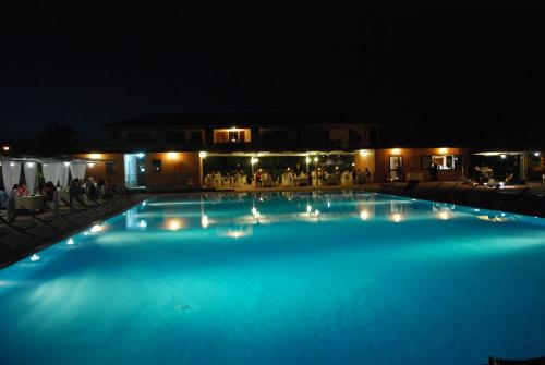 a large blue swimming pool at night with lights at Hotel Borgo degli Olivi in Riotorto