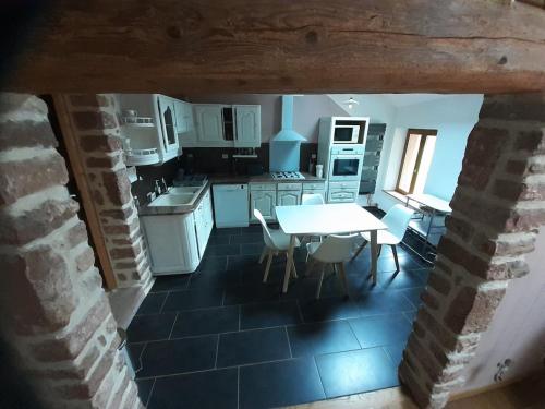 une cuisine avec des armoires blanches et une table et des chaises dans l'établissement Gîte Vosges Alsace 5 voyageurs, à Raon-lès-Leau