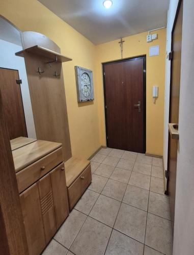 a bathroom with a wooden door and a tiled floor at Garsónka s klímou v Senici in Senica