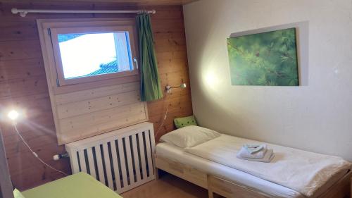a small room with a small bed and a window at Haus Rhodania in Albinen