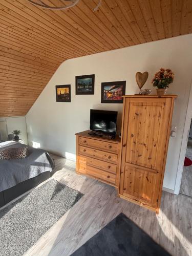 a bedroom with a bed and a television on a wooden cabinet at Am Wäldchen in Hechthausen