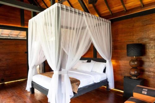 a bedroom with a canopy bed with white curtains at Villa Ssweta 2 in Canggu