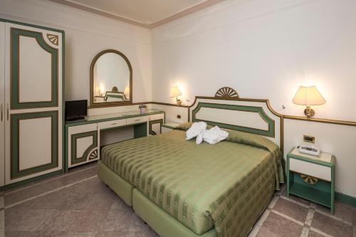 a bedroom with a bed and a desk and a mirror at Grand Hotel Terme in Riolo Terme