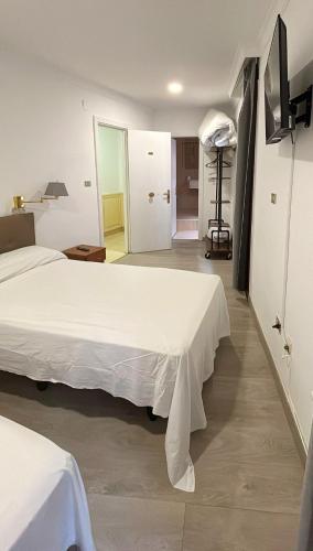 Un dormitorio con dos camas y una puerta a una habitación. en Habitaciones triple familiar HOTEL LAUAXETA, en Mungia