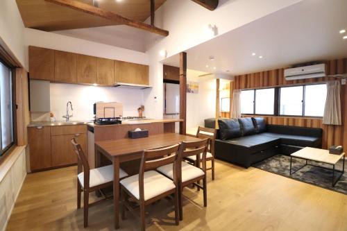 a kitchen and living room with a table and a couch at H-Shinsaibashi アッシュ心斎橋 in Osaka