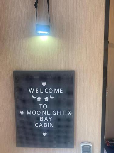 a sign on a wall that says welcome to moonlit bay cabin at Moon Bay Cabin by Tiny Away in South Arm