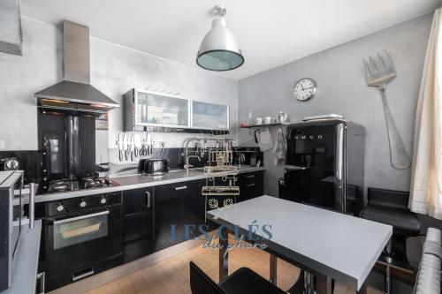 une cuisine avec des appareils en noir et blanc et une table dans l'établissement SUPERBE VILLA ARMAND, à Le Touquet-Paris-Plage