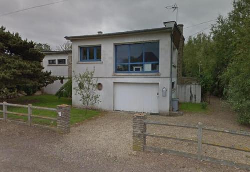 une maison blanche avec une grande fenêtre et une clôture dans l'établissement Le Radeau Maison 50m de la Mer - 6P - 3 Chambres 2 SDB, à Ver-sur-Mer