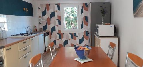 une cuisine avec une table avec un bol de fruits dessus dans l'établissement Cap Corse - Maison à 500m de la plage - Logement entier, à Grillasca