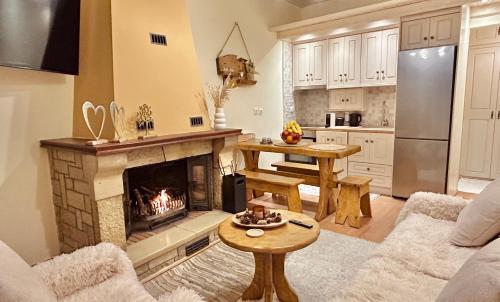 a living room with a fireplace and a kitchen at Sokaki Guesthouse in Arachova
