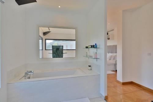 une salle de bain blanche avec une baignoire et un miroir dans l'établissement Villa Bella Vista - Luxe - Piscine et Sérénité au Cœur du Cannet, au Cannet