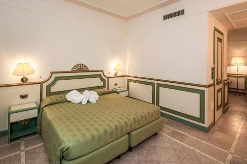 a bedroom with a bed with two towels on it at Grand Hotel Terme in Riolo Terme