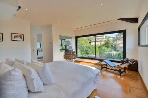 une chambre avec un lit blanc et une grande fenêtre dans l'établissement Villa Bella Vista - Luxe - Piscine et Sérénité au Cœur du Cannet, au Cannet