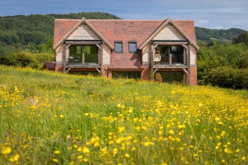 an old house sitting in a field of flowers at Woodlands Malvern B and B in Longley Green